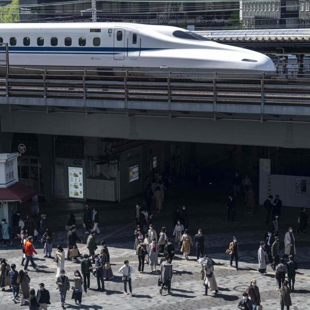 Ein Shinkansen-Hochgeschwindigkeitszug fährt über eine belebte Straße in Japan.