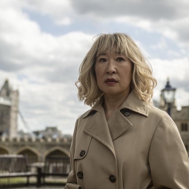 Sandra Oh vor dem Tower of London, gekleidet in einem Trenchcoat.