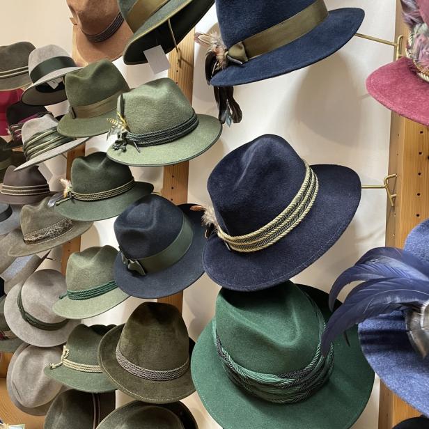 Eine Auswahl an traditionellen Trachtenhüten hängt an einer Wand.