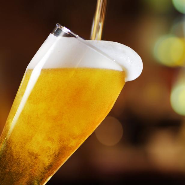 Ein Glas Bier wird eingeschenkt, mit Schaumkrone.