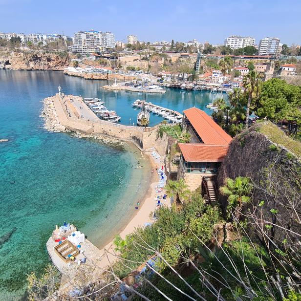 Blick auf den Hafen von Antalya mit Booten und türkisfarbenem Wasser.