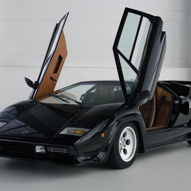 Ein schwarzer Lamborghini Countach mit geöffneten Flügeltüren steht in einem Studio.