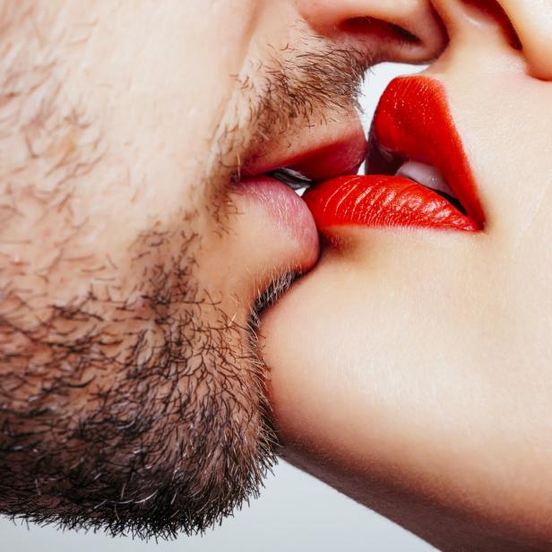 Ein Paar küsst sich; die Frau trägt roten Lippenstift.