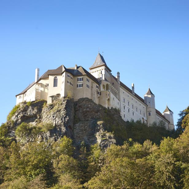 Burg Clam thront auf einem Felsen über dem grünen Umland.