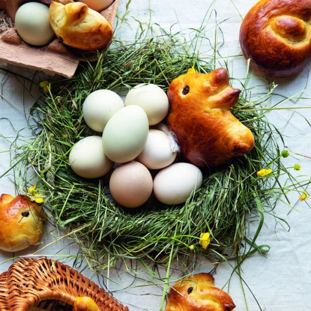 Osterbrot in Hasenform und Eier in einem Nest aus Heu.