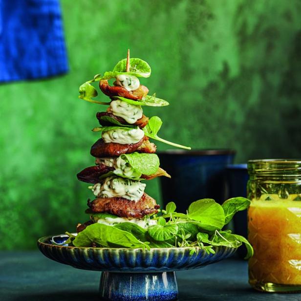 Ein Turm aus Fleisch, Salat und Sauce auf einem blauen Teller.