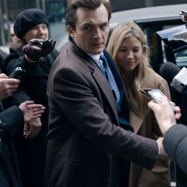 Ein Mann und eine Frau werden von Reportern und Fotografen umringt.
