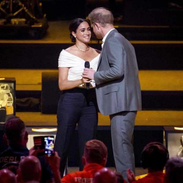 Meghan Markle und Prinz Harry auf einer Bühne vor Publikum.