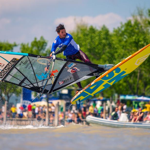 Ein Windsurfer springt mit seinem Board über das Wasser.