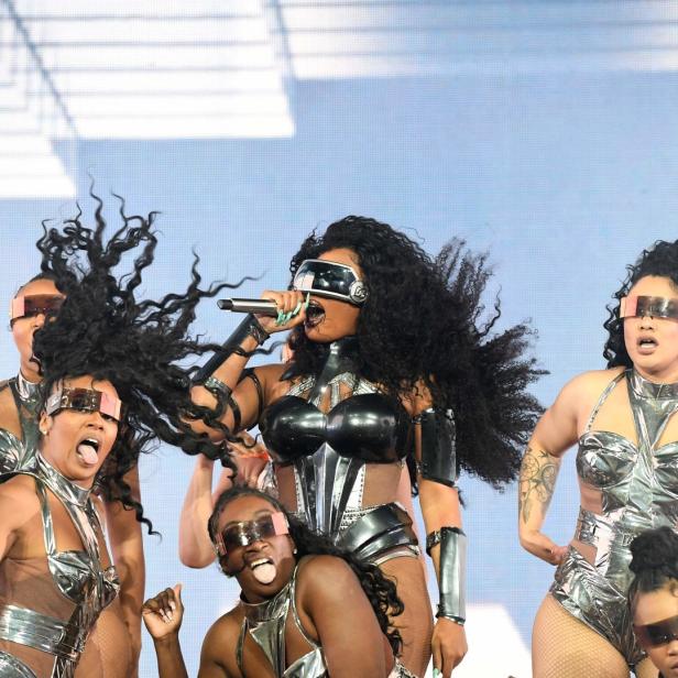 Megan Thee Stallion tritt mit Tänzerinnen in futuristischen Outfits auf einer Bühne auf.