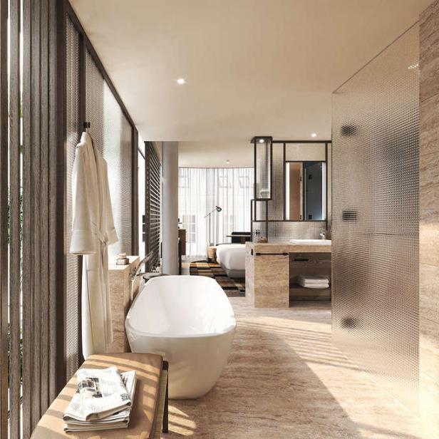 Ein Badezimmer mit freistehender Badewanne und Blick auf eine grüne Außenanlage.