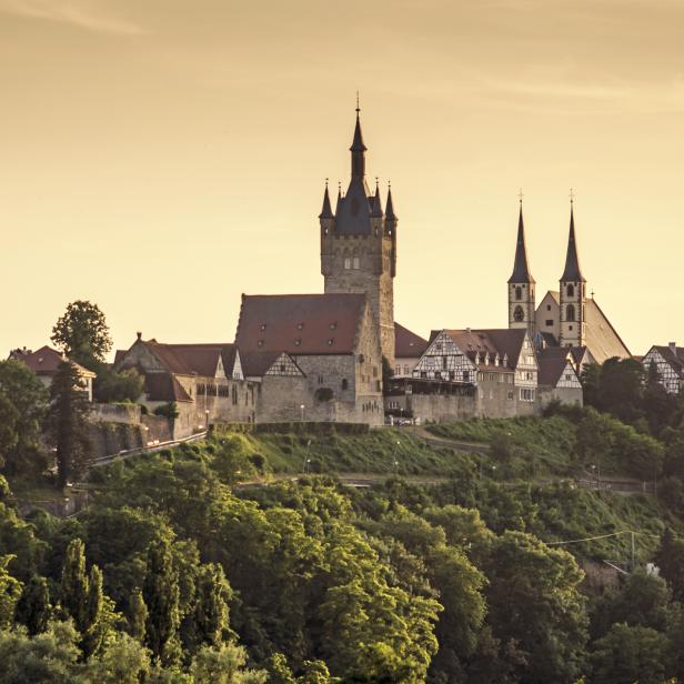 Blick auf eine mittelalterliche Stadt mit Burg und Kirche auf einem Hügel.