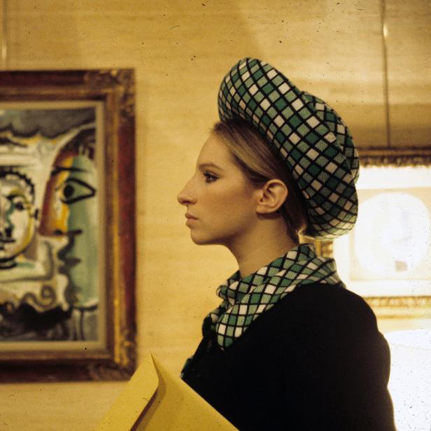 Barbra Streisand vor einem Gemälde mit zwei Gesichtern, möglicherweise von Picasso.