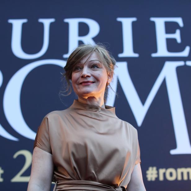 Eine Frau im goldenen Kleid vor dem Hintergrund der Romy-Preisverleihung 2018.