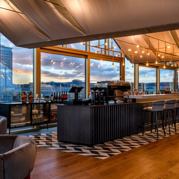 Eine Bar mit Blick auf eine Stadt bei Sonnenuntergang.