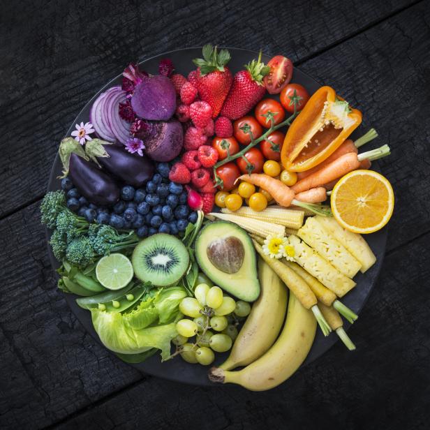 Ein Teller mit einer farbenfrohen Auswahl an Obst und Gemüse, angeordnet wie ein Regenbogen.
