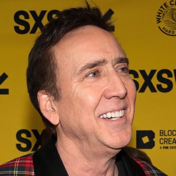 Nicolas Cage lächelt vor einem gelben Hintergrund mit SXSW-Logos.