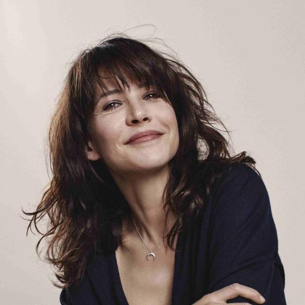 Sophie Marceau lächelt mit verschränkten Armen in die Kamera.