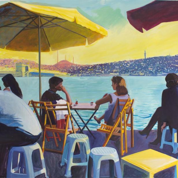 Eine Gruppe von Menschen sitzt in einem Café am Wasser mit Blick auf Istanbul.