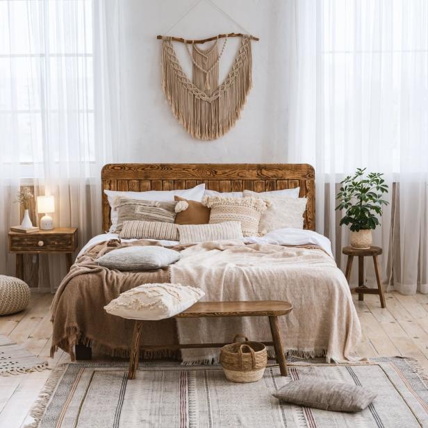Ein helles Schlafzimmer mit einem Holzbett und vielen Kissen im Boho-Stil.
