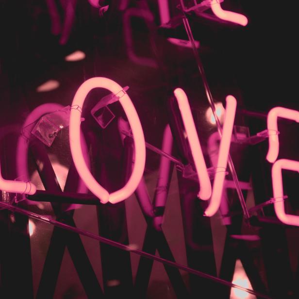 Ein rosafarbenes Neonlicht formt das Wort „Love“.