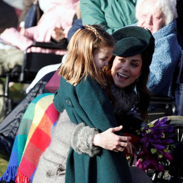 Kate Middleton umarmt Prinzessin Charlotte, die einen grünen Mantel trägt.