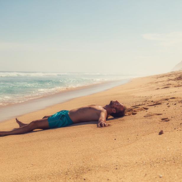 Ein Mann liegt am Strand und entspannt sich in der Sonne.