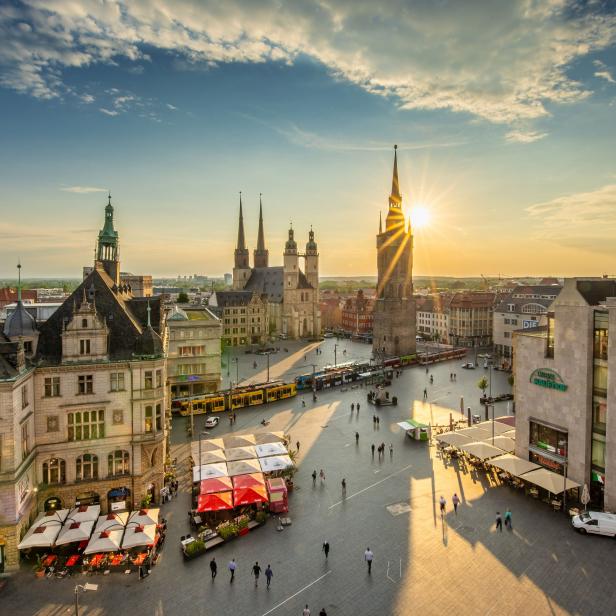 Blick auf den Marktplatz von Halle (Saale) mit der Marktkirche und Passanten im Abendlicht.