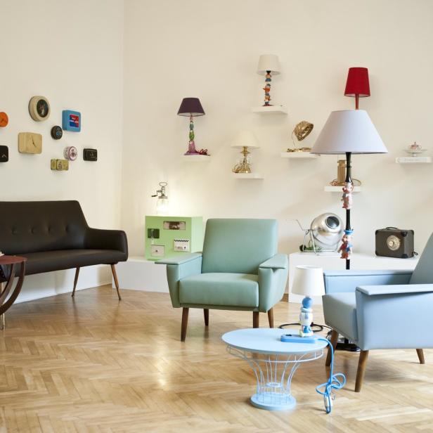 Ein Wohnzimmer mit einem braunen Sofa, pastellfarbenen Sesseln und ungewöhnlichen Lampen.
