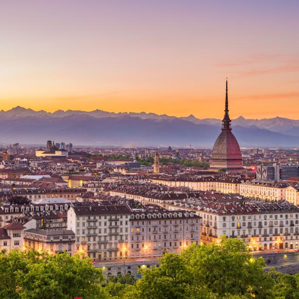 Blick auf Turin bei Sonnenuntergang mit der Mole Antonelliana und den Alpen im Hintergrund.