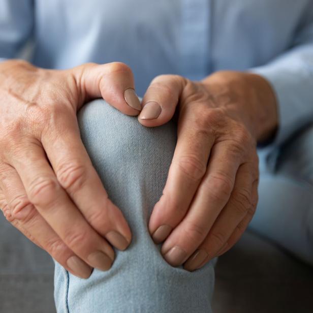 Eine ältere Frau berührt ihr Knie und leidet an Schmerzen durch Arthrose.