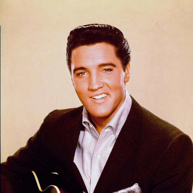 Elvis Presley mit Gitarre in einem dunklen Anzug.