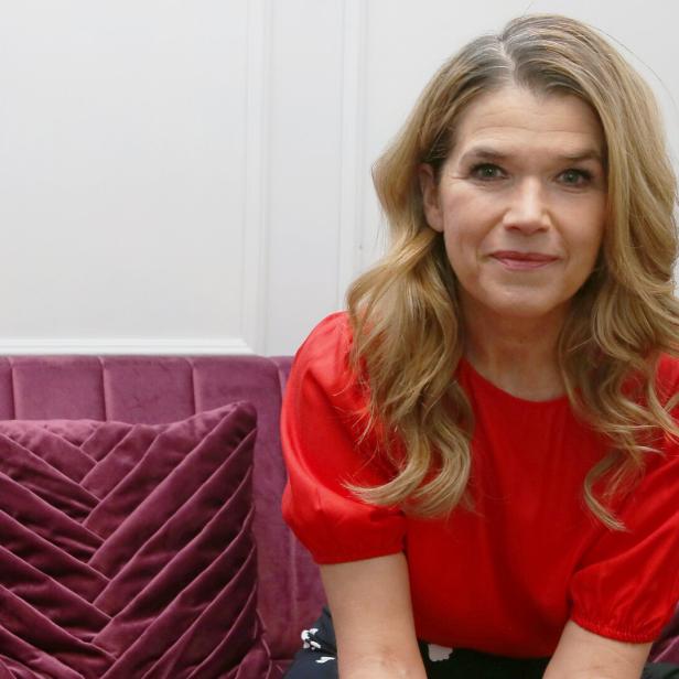 Anke Engelke sitzt auf einem lila Sofa.