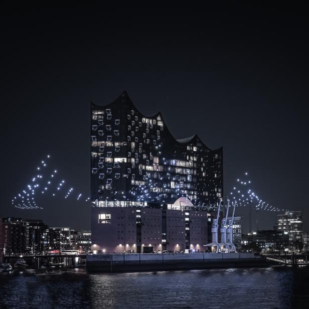 Die Elbphilharmonie in Hamburg bei Nacht mit einer Drohnen-Lichtshow.