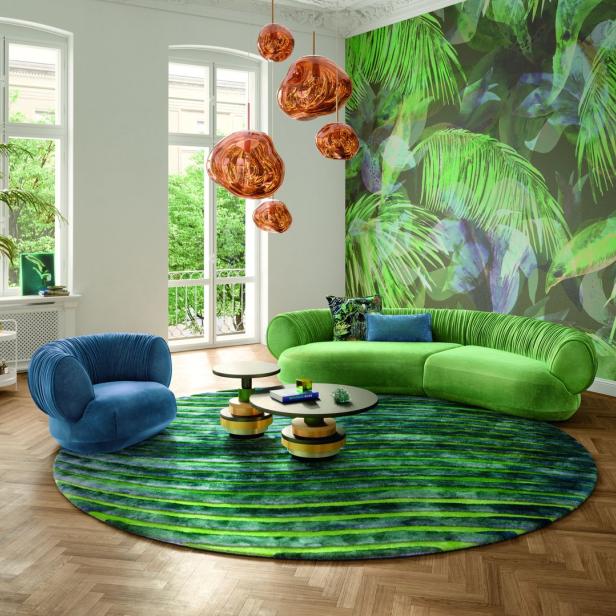 Ein Wohnzimmer mit grünen und blauen Möbeln und einer Dschungeltapete.