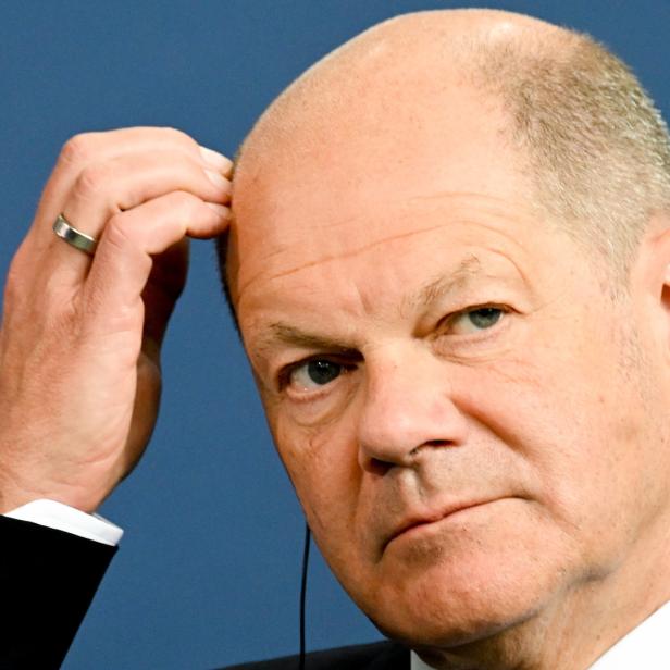 Olaf Scholz blickt nachdenklich und berührt seine Stirn.