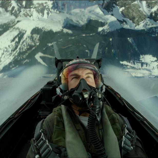 Tom Cruise als Pilot in einem Kampfjet über schneebedeckten Bergen.
