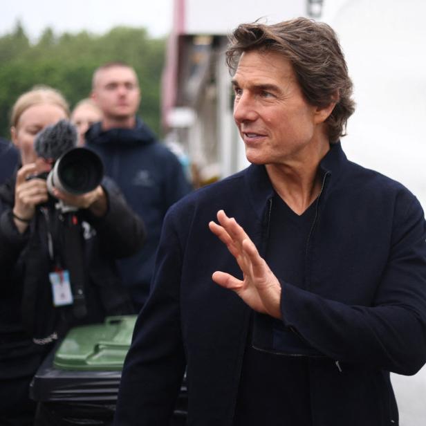 Tom Cruise bei einer Veranstaltung mit Fotografen im Hintergrund.