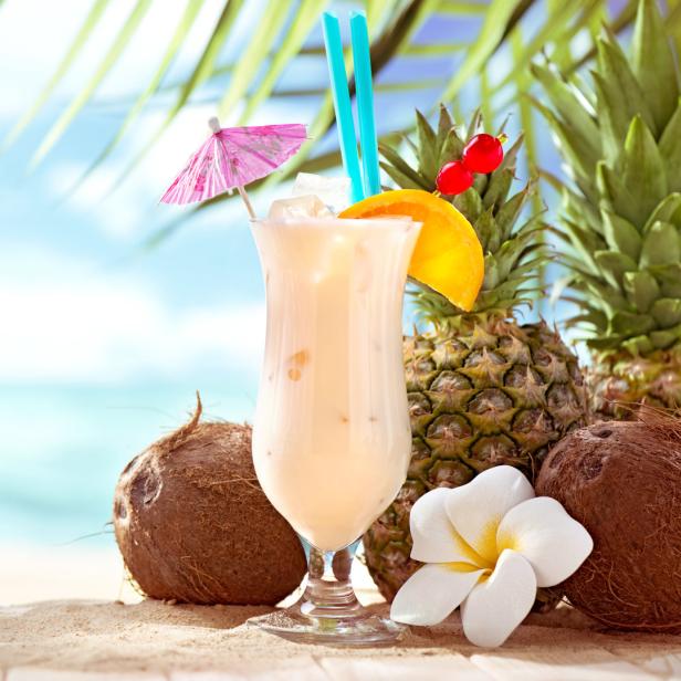 Ein Piña Colada Cocktail mit Ananas und Kokosnüssen am Strand.