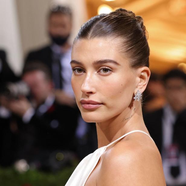 Nahaufnahme von Hailey Bieber mit hochgesteckten Haaren und einem weißen Kleid.