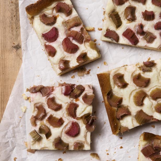 Mehrere Stücke Rhabarberkuchen auf einem Stück Papier auf einem Holztisch.