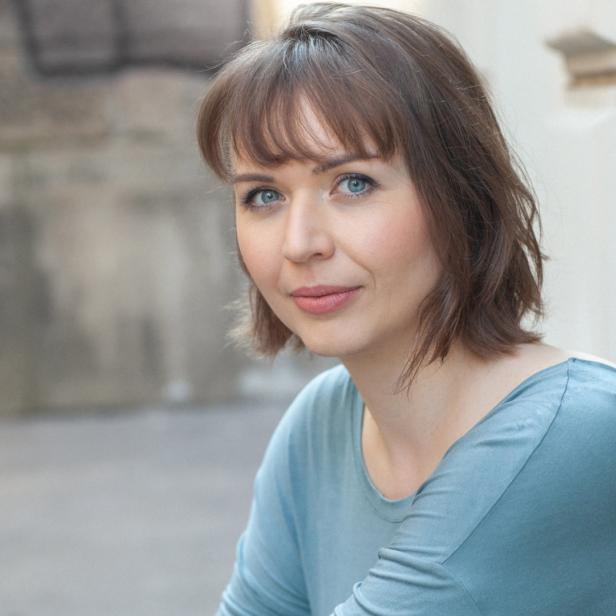 Porträt einer Frau mit braunen Haaren und blauen Augen.