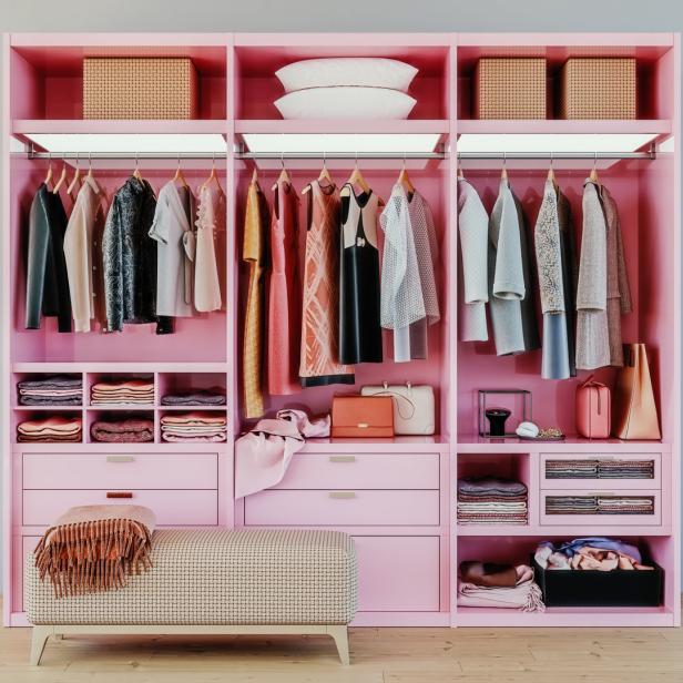 Ein rosa begehbarer Kleiderschrank mit Kleidung, Handtaschen und einer Bank.
