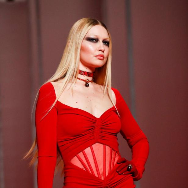 Gigi Hadid präsentiert ein rotes Kleid mit passender Handtasche auf dem Laufsteg.