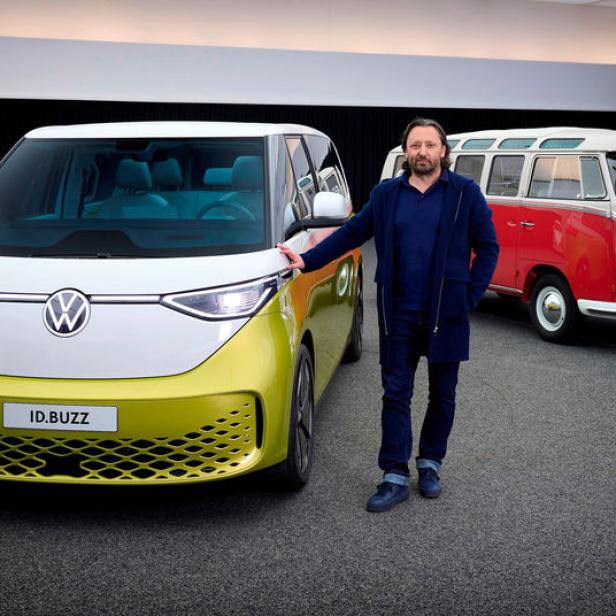 Ein Mann steht neben einem gelb-weißen VW ID.Buzz, im Hintergrund ein roter VW Bulli.