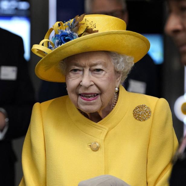 Königin Elisabeth II. in einem gelben Kostüm mit passendem Hut und Gehstock.