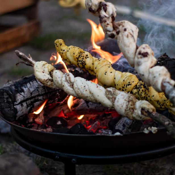Stockbrot wird über einem Lagerfeuer gebacken.