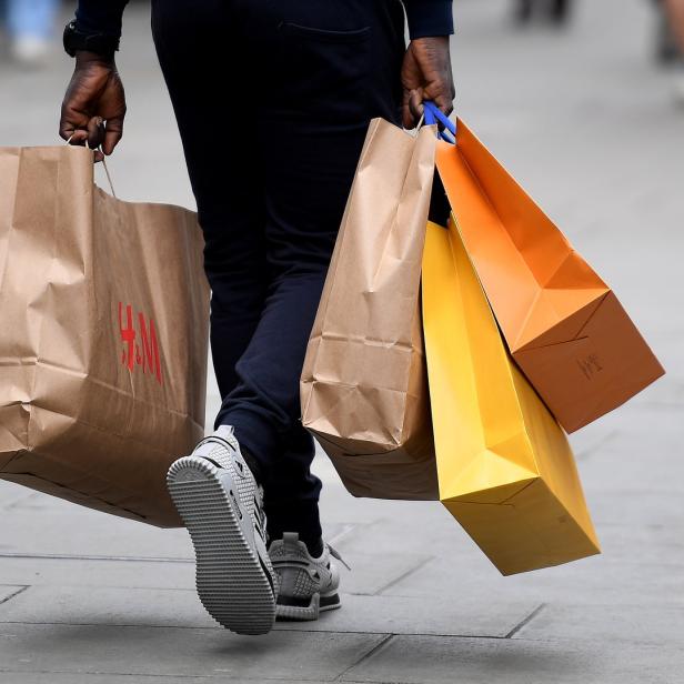 Eine Person trägt Einkaufstüten von H&M und anderen Geschäften.