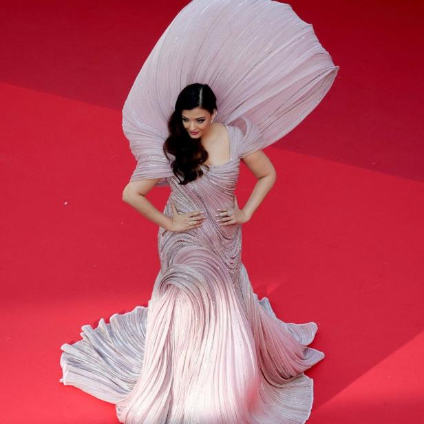Aishwarya Rai trägt ein extravagantes, hellrosa Kleid auf einem roten Teppich.
