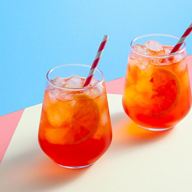 Spritz-Cocktails in Gläsern mit Eis und Orangenscheibe auf trendigem, farbenfrohem Hintergrund. Kreatives, minimales Konzept.